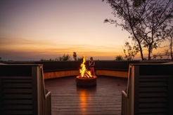 Woman sitting by a fireplace at Matt Wrights Top End Safari Camp